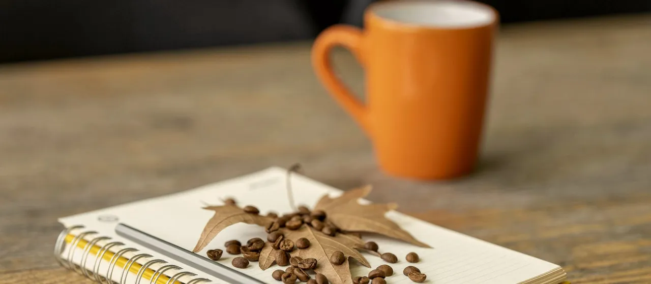 A notebook and coffee on a worn wooden table